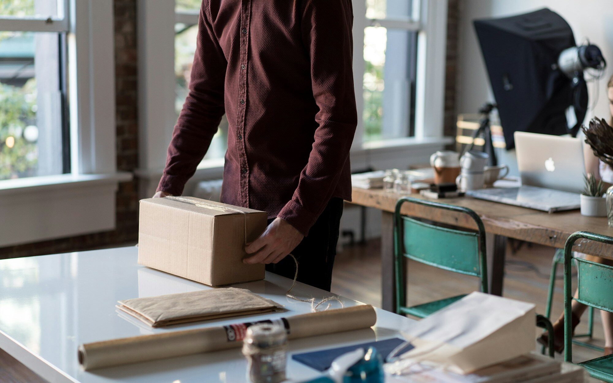 Person verpackt im Büro ein Paket für den Versand